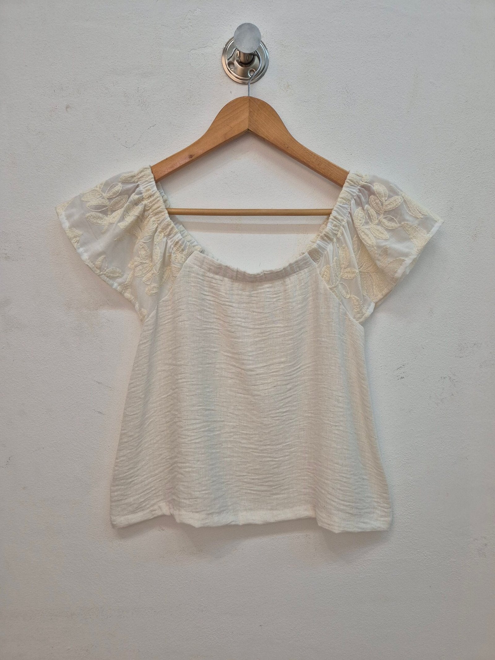 Blusa blanca de algodón con manga corta volante y escote redondo