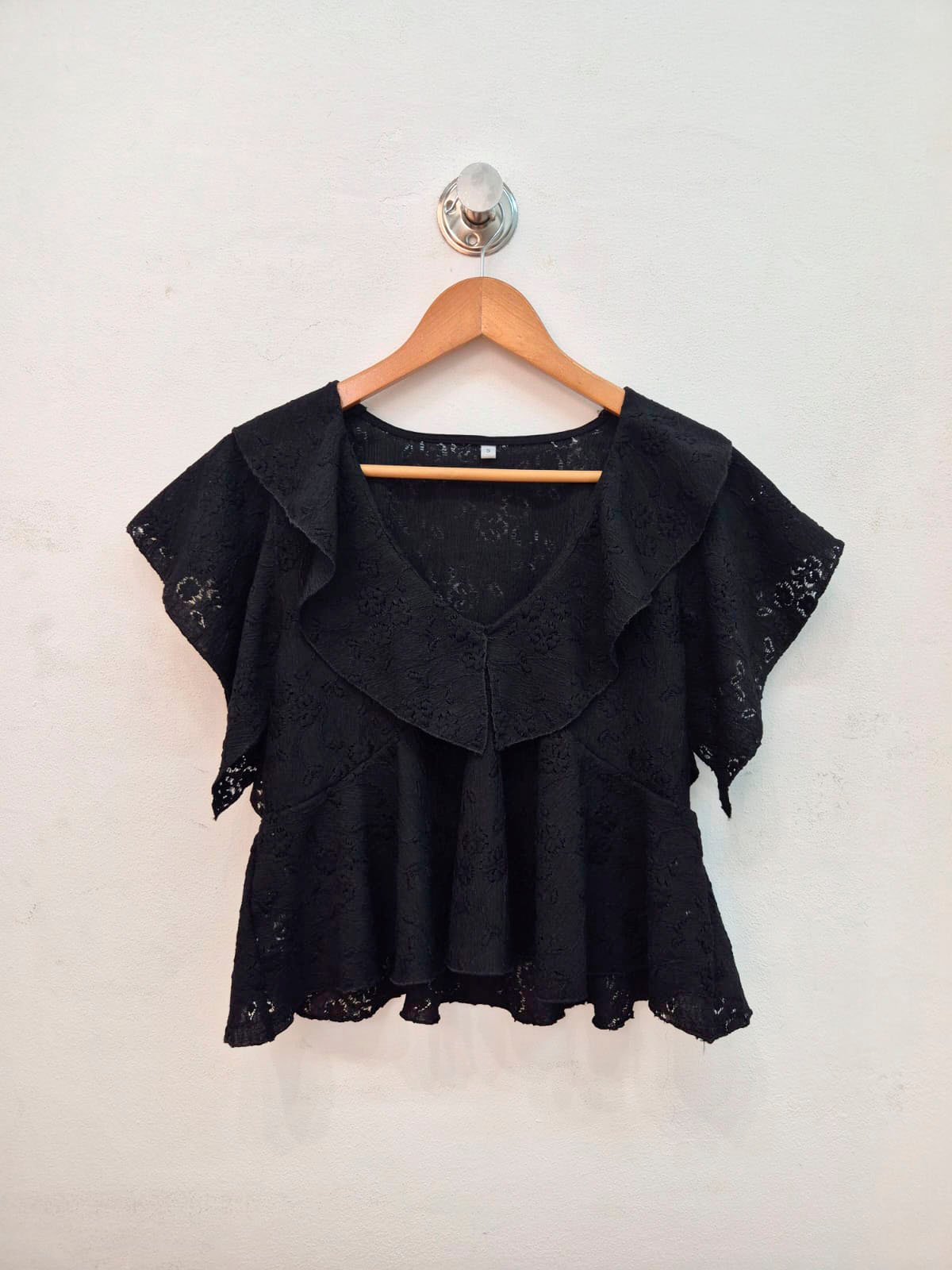 Blusa negra de encaje con volante y manga corta