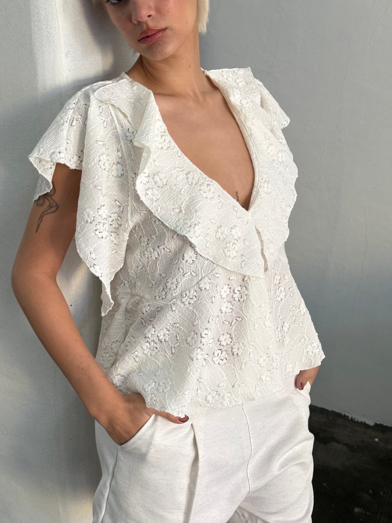 Blusa blanca de encaje con volados y escote en V profundo