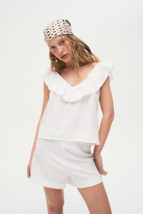 Blusa blanca de algodón con volado en escote y manga corta