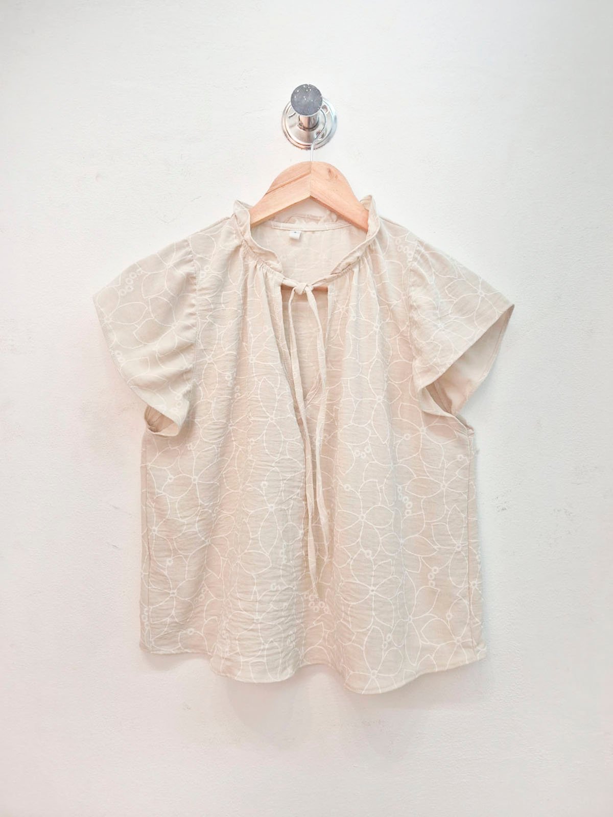 Blusa beige con estampado geométrico, escote redondo y manga corta