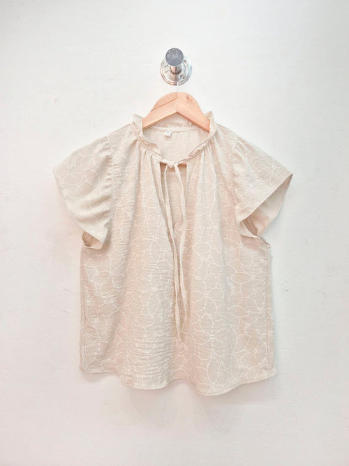 Blusa beige con estampado geométrico, escote redondo y manga corta