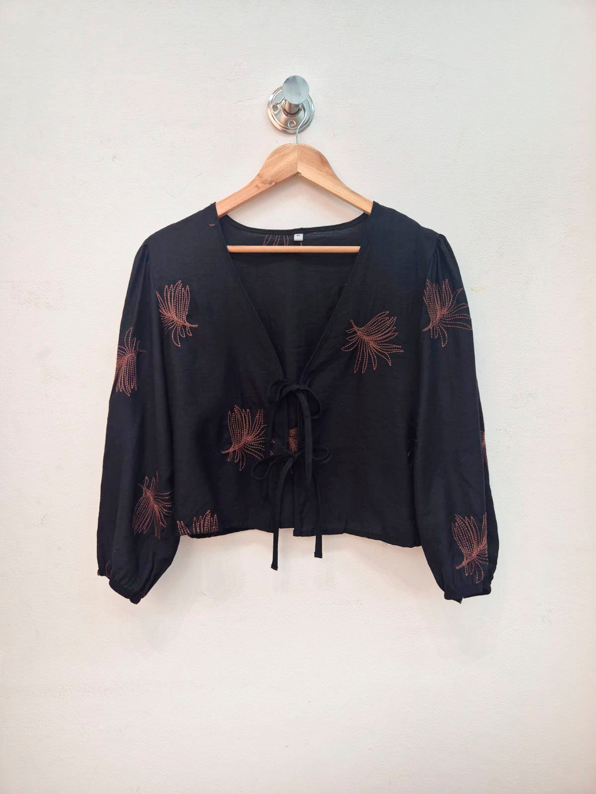Blusa negra con escote en V y estampado de flores terracota en mangas