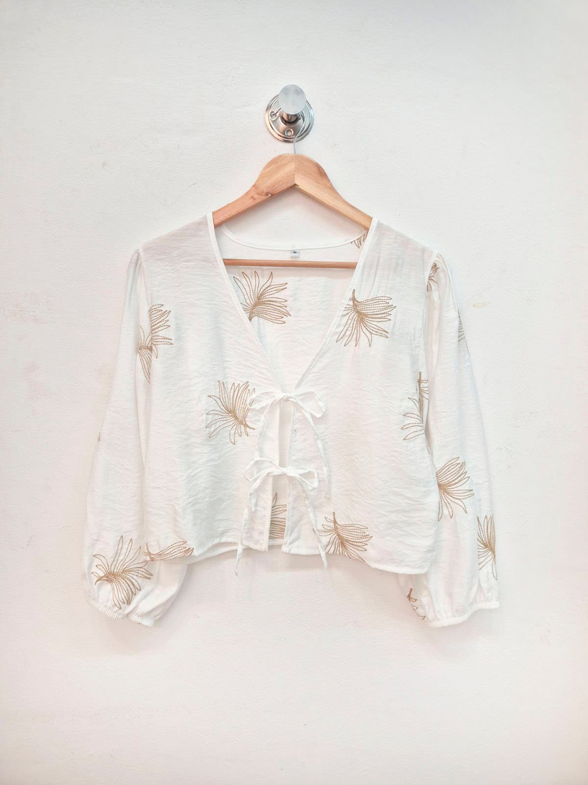 Blusa blanca con estampado de flores beige y cierre frontal