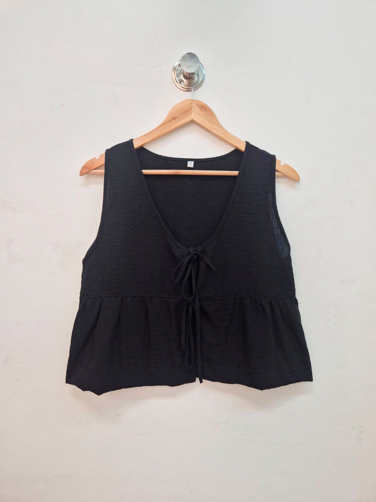 Blusa negra sin mangas con escote en V y lazo frontal