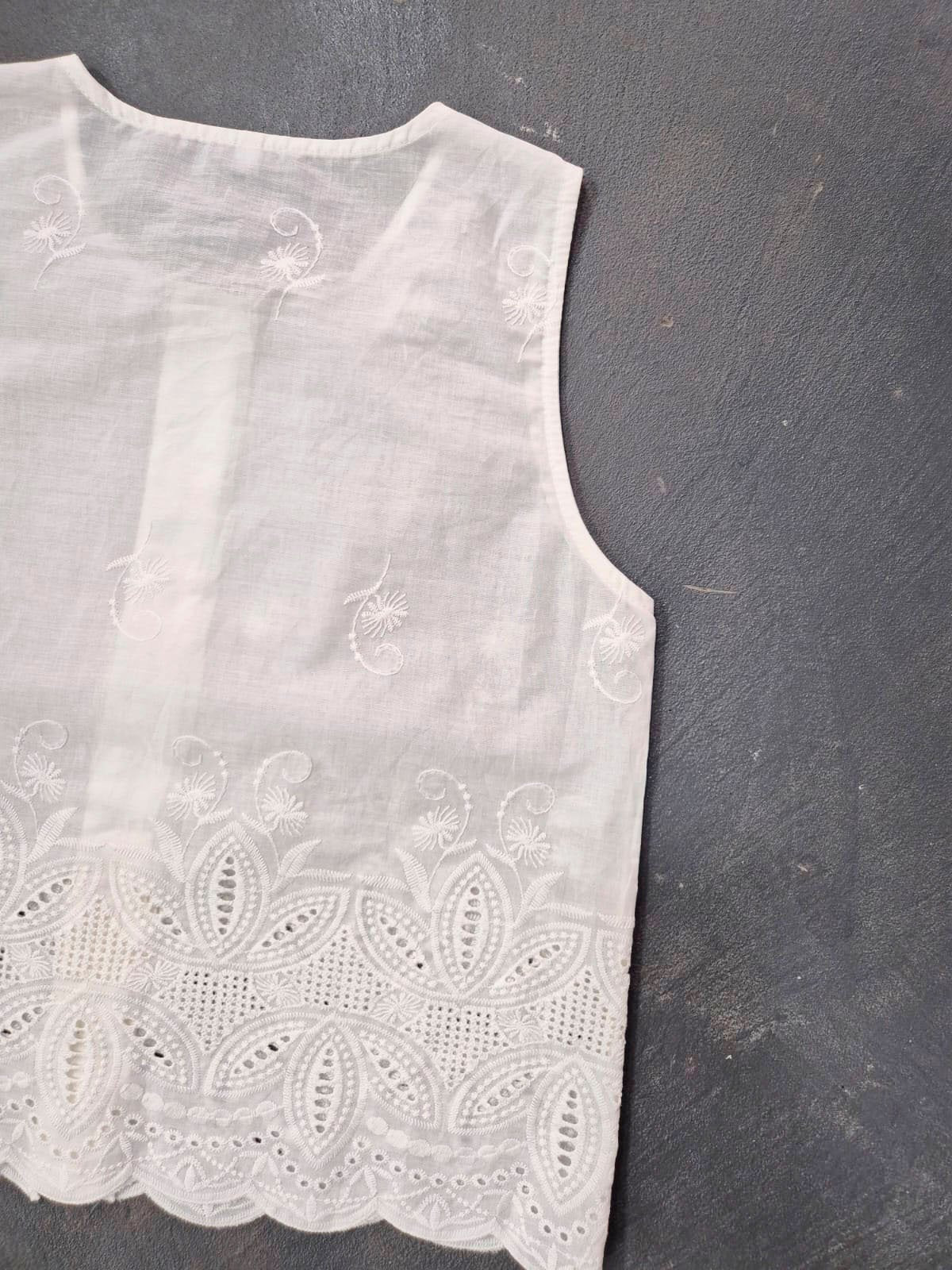 Blusa blanca sin mangas con bordado de flores y encaje calado
