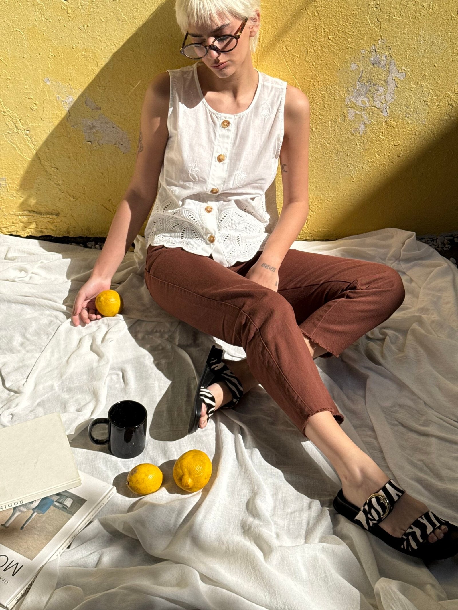 Blusa blanca sin mangas con botones y detalle de encaje en cintura
