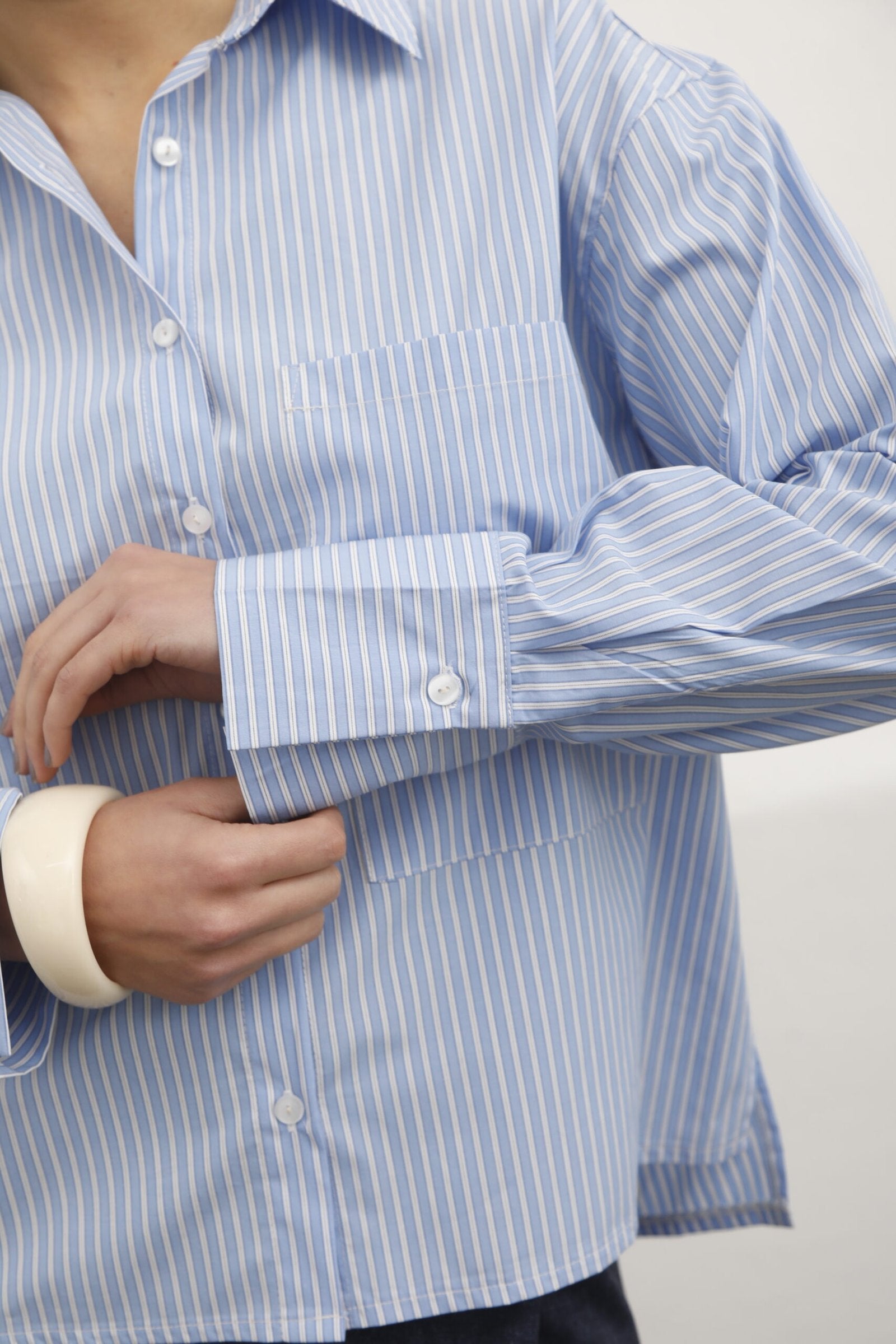 Camisa azul con rayas blancas verticales y botones blancos