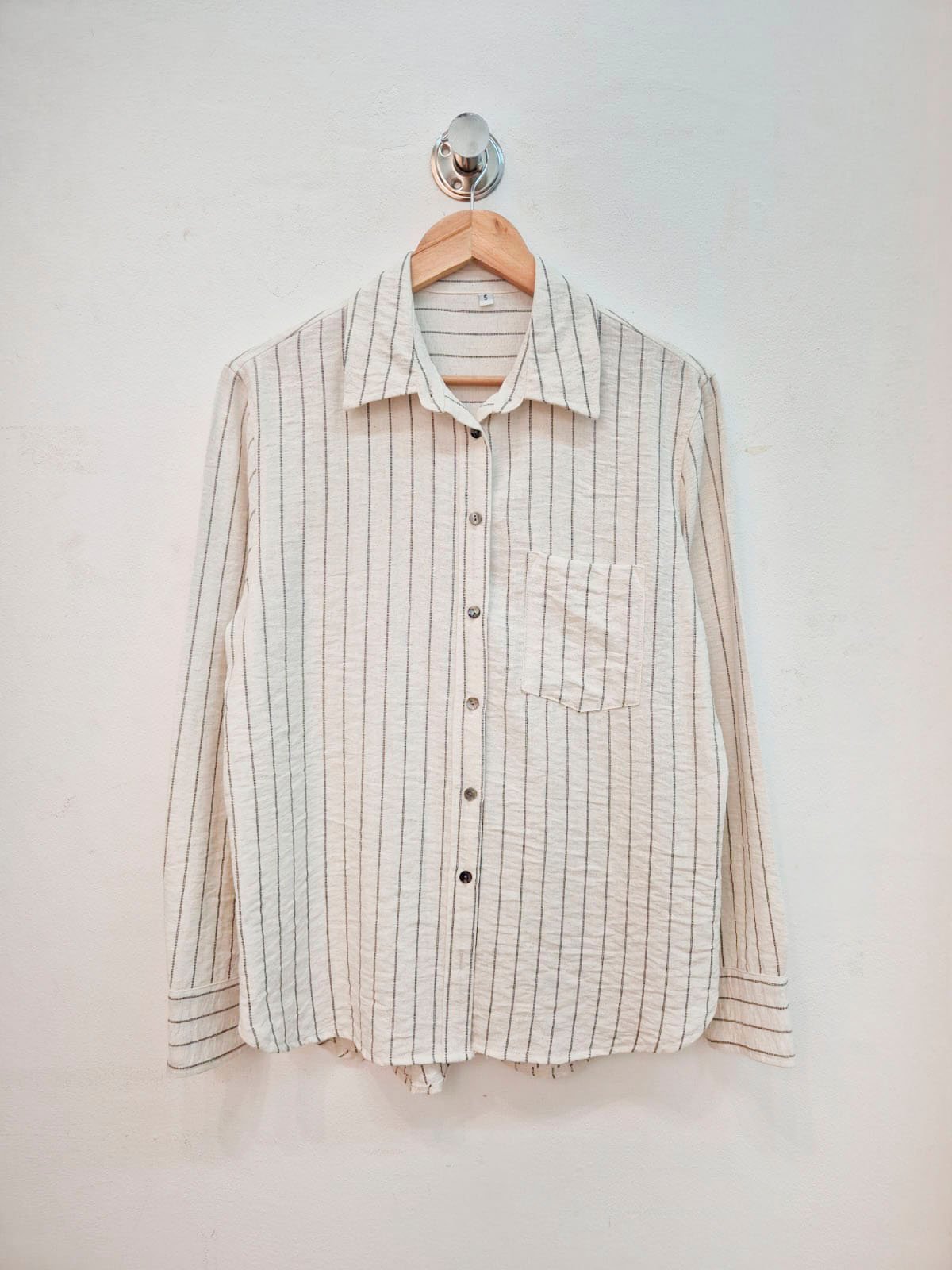 Camisa beige con rayas verticales grises, manga larga y bolsillo delantero
