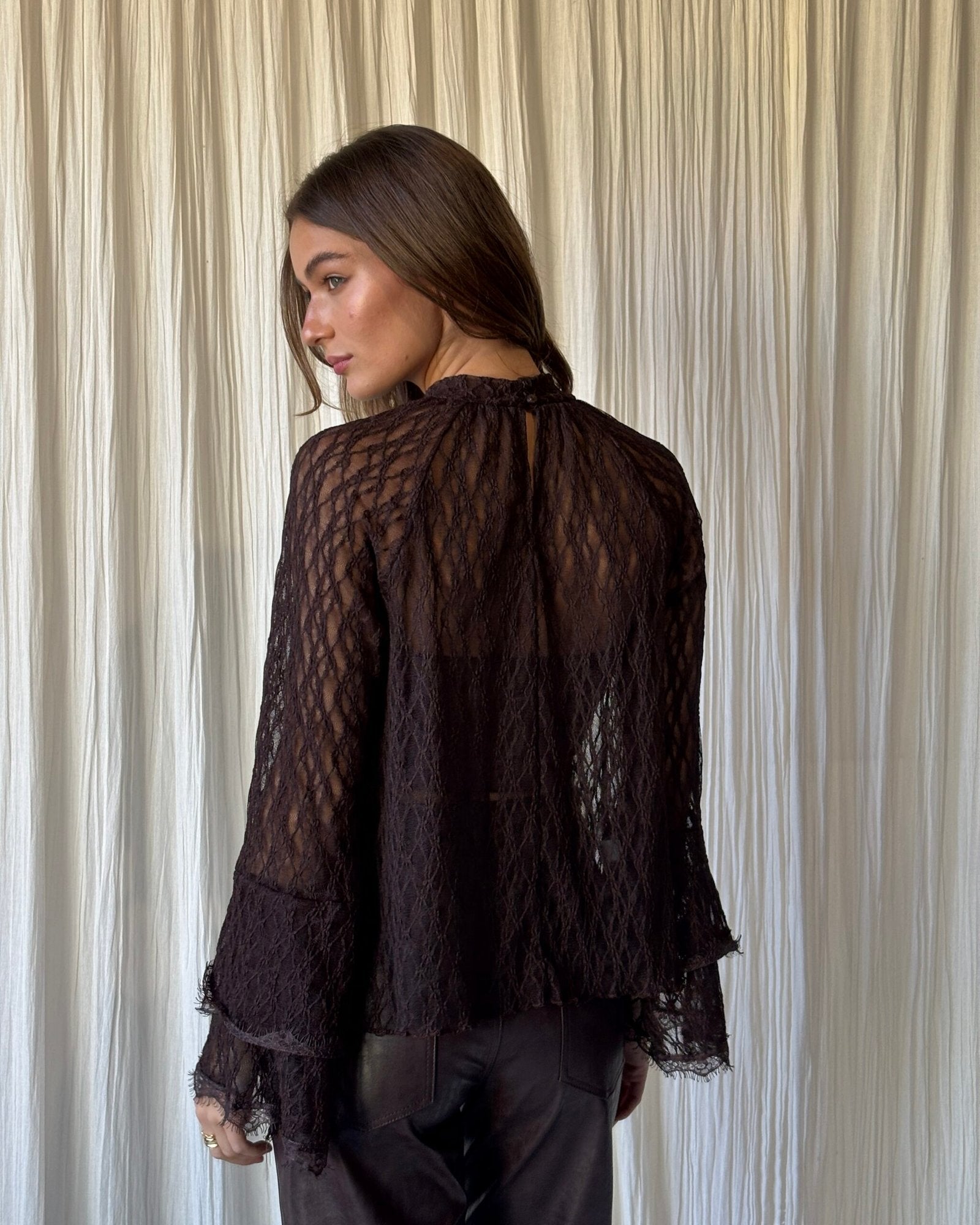 Blusa negra de encaje con mangas largas y puño fruncido