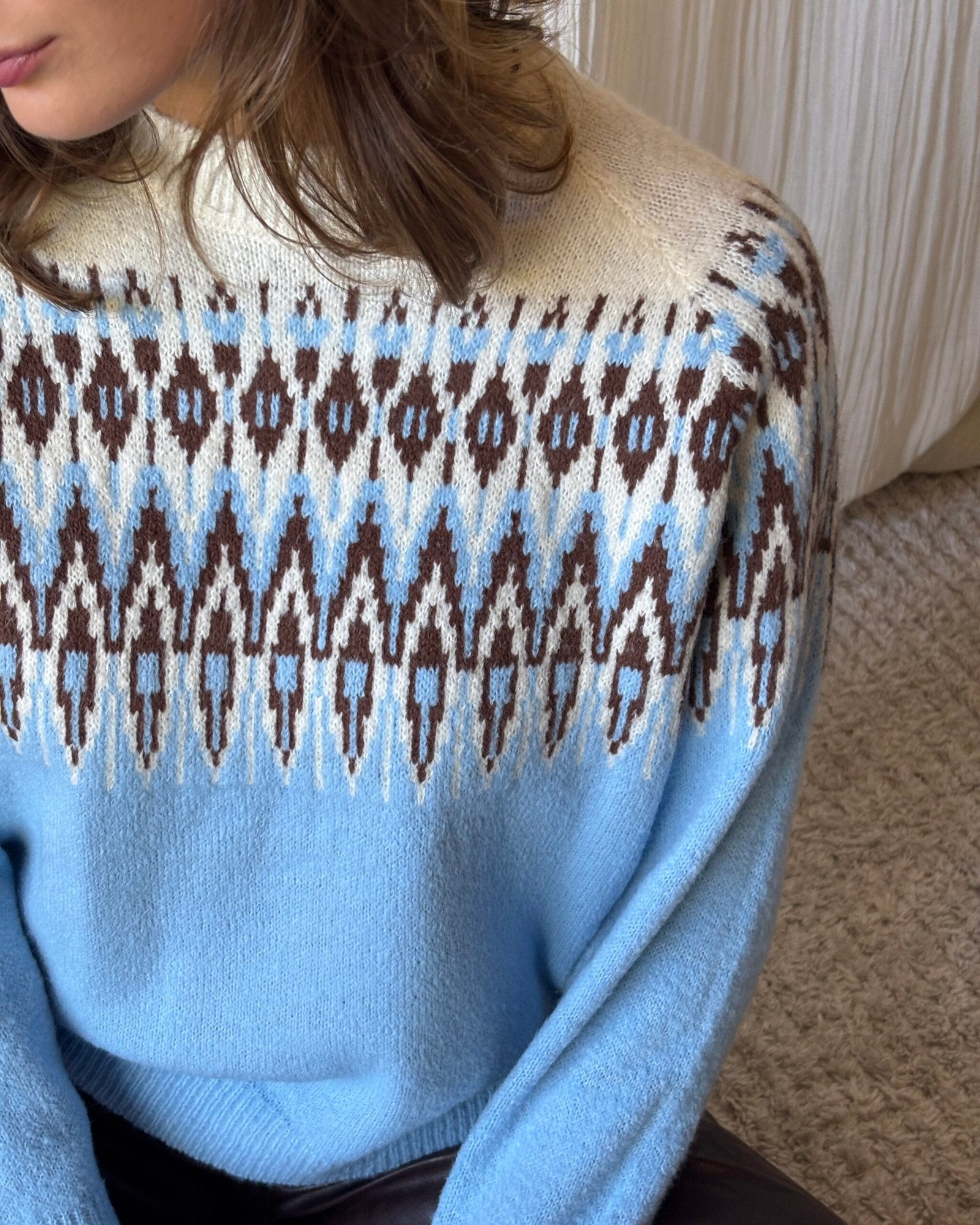 Sweater azul celeste con patrón geométrico marrón y blanco en el pecho