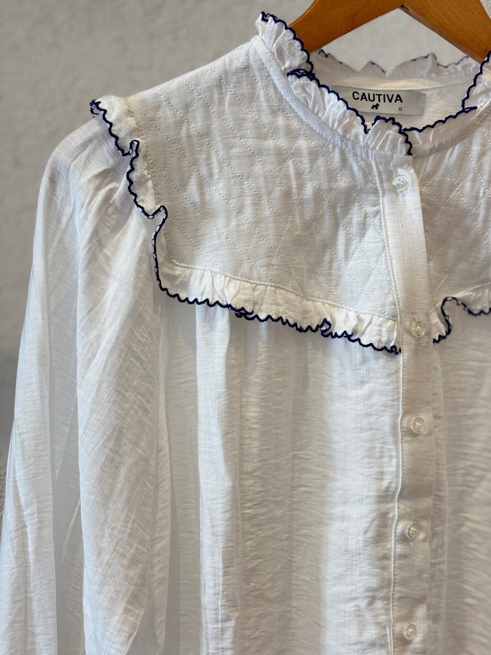 Camisa blanca de algodón con volados y ribete azul marino