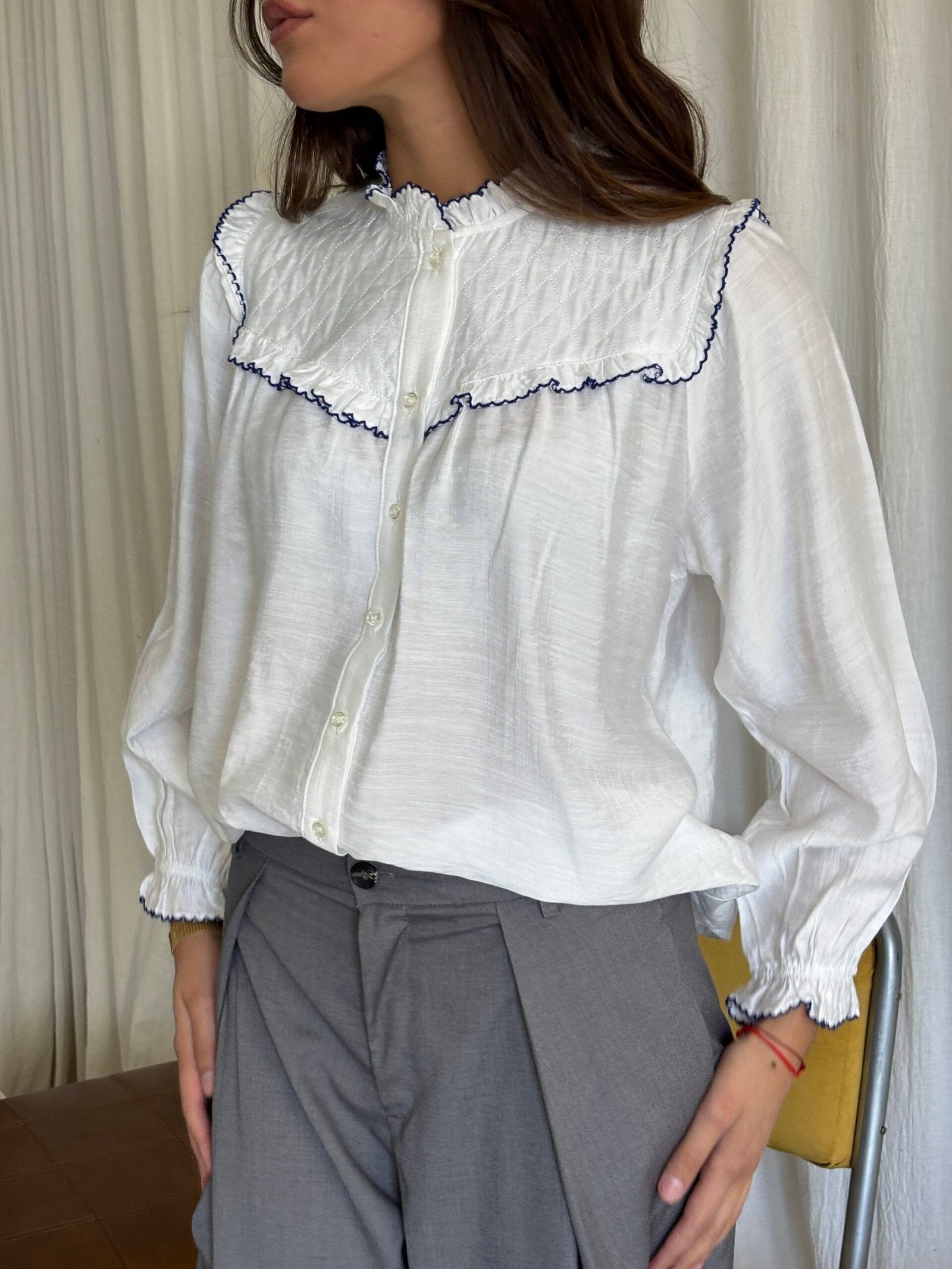 Camisa blanca con cuello volante ondulado y ribete azul marino