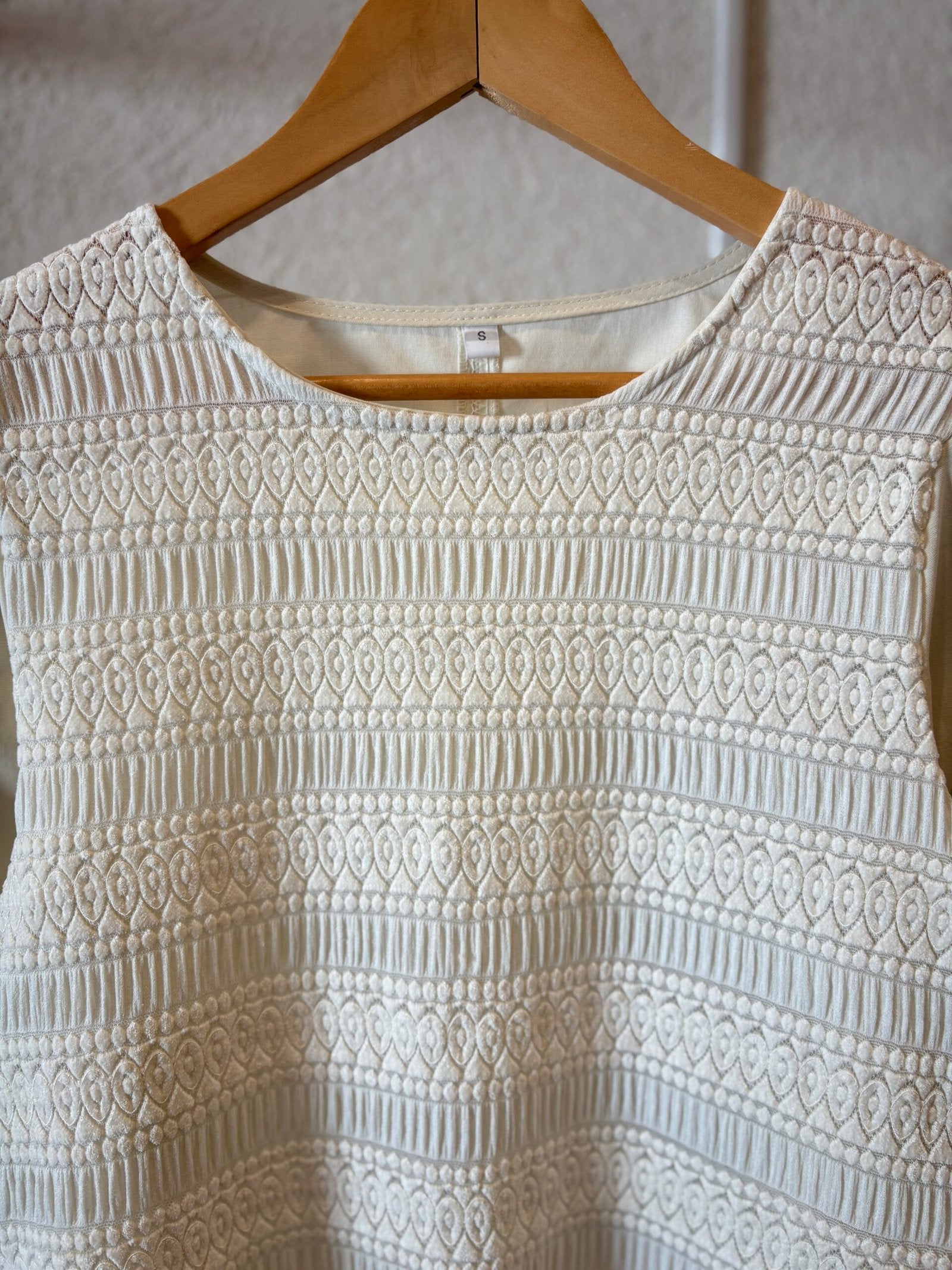 Blusa crema con textura acanalada y patrón geométrico, cuello redondo