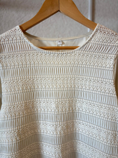 Blusa crema con textura acanalada y patrón geométrico, cuello redondo