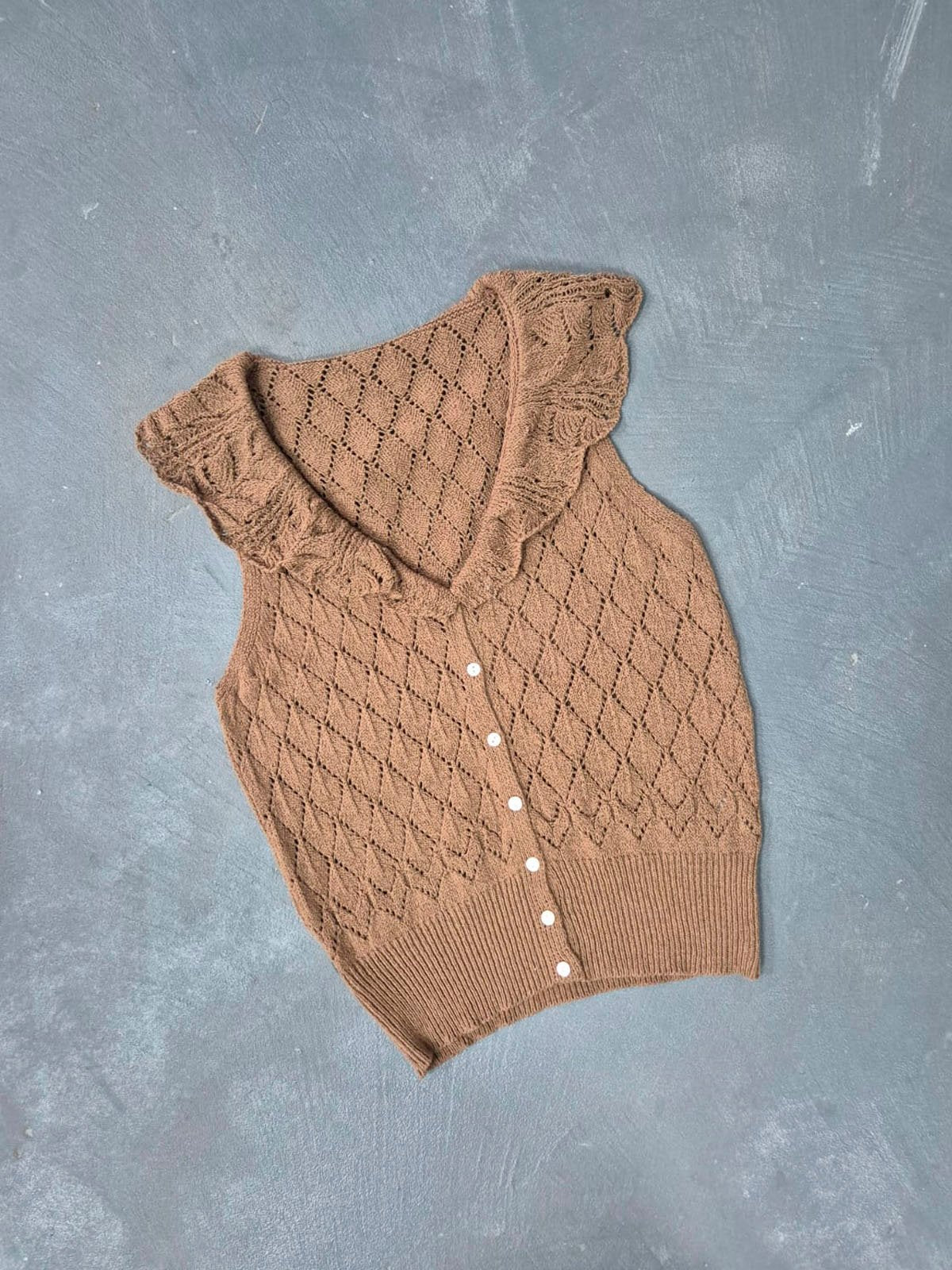 Musculosa beige tejida con volante en escote y botones blancos