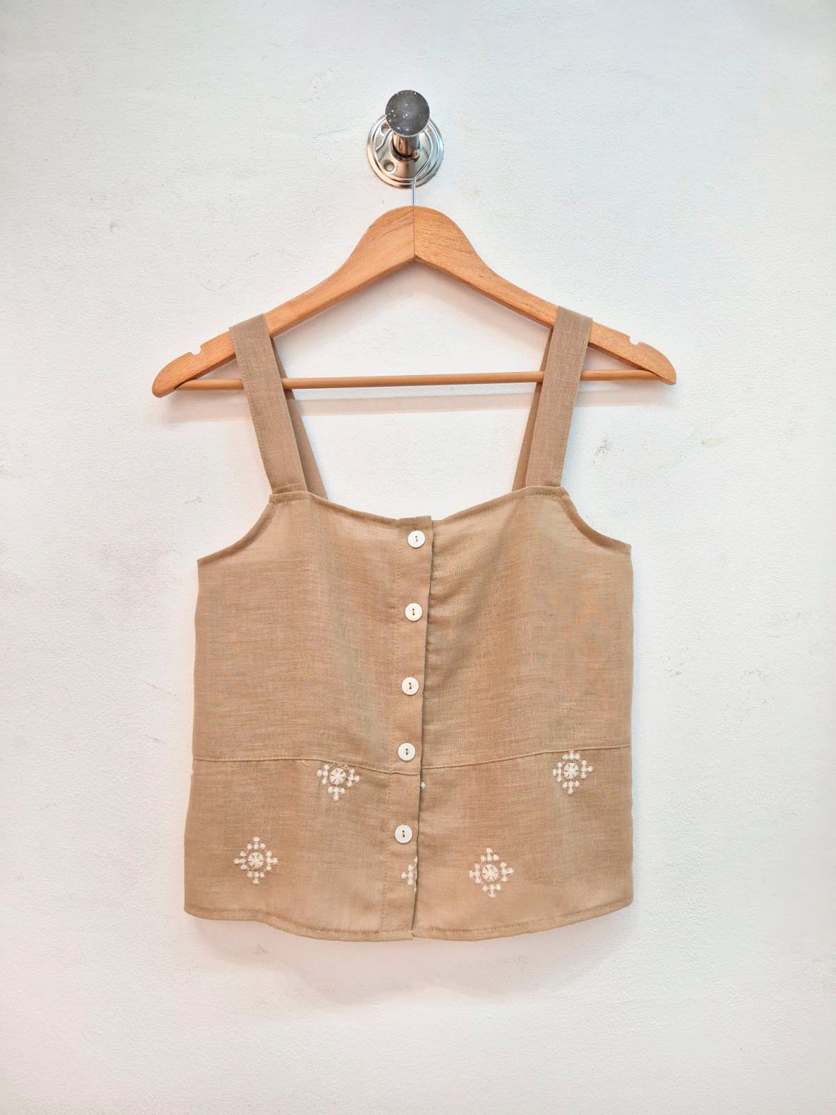 Top beige con botones frontales y bordados decorativos blancos