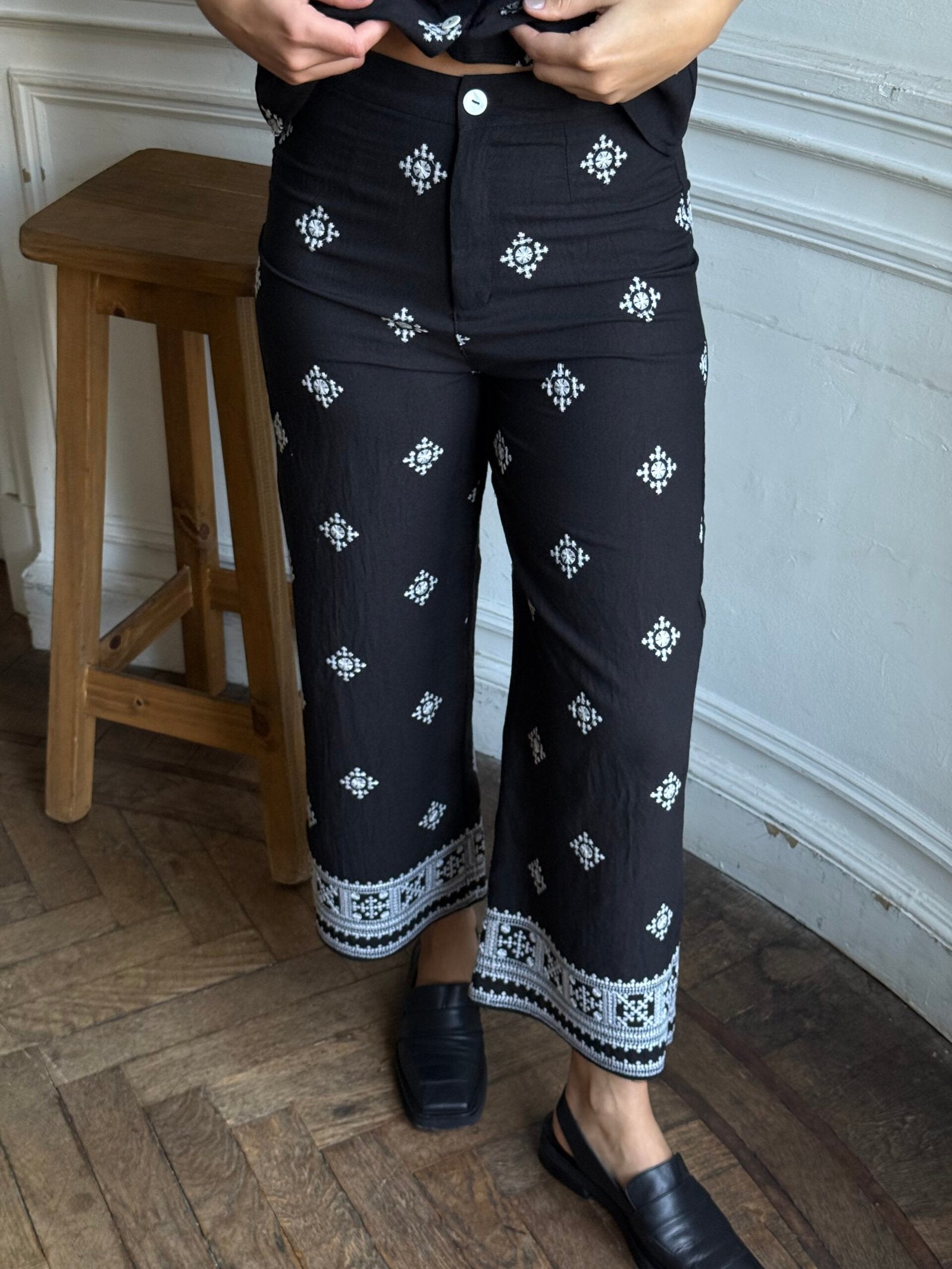 Pantalón negro con estampado geométrico blanco y ruedo bordado