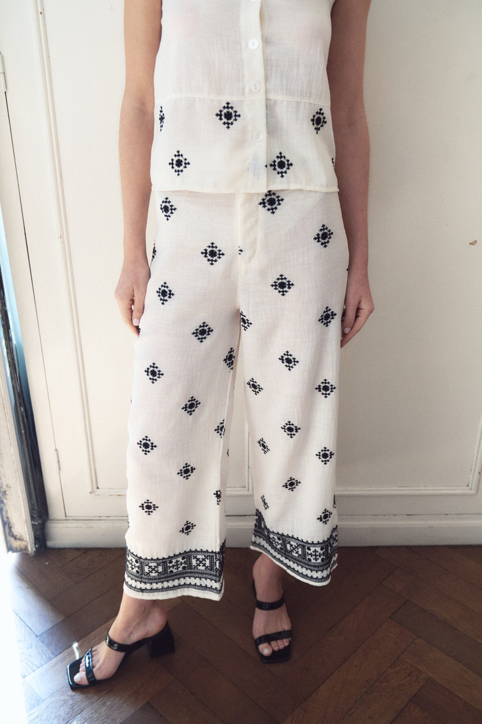 Pantalón blanco estampado con motivos geométricos negros y tira decorativa