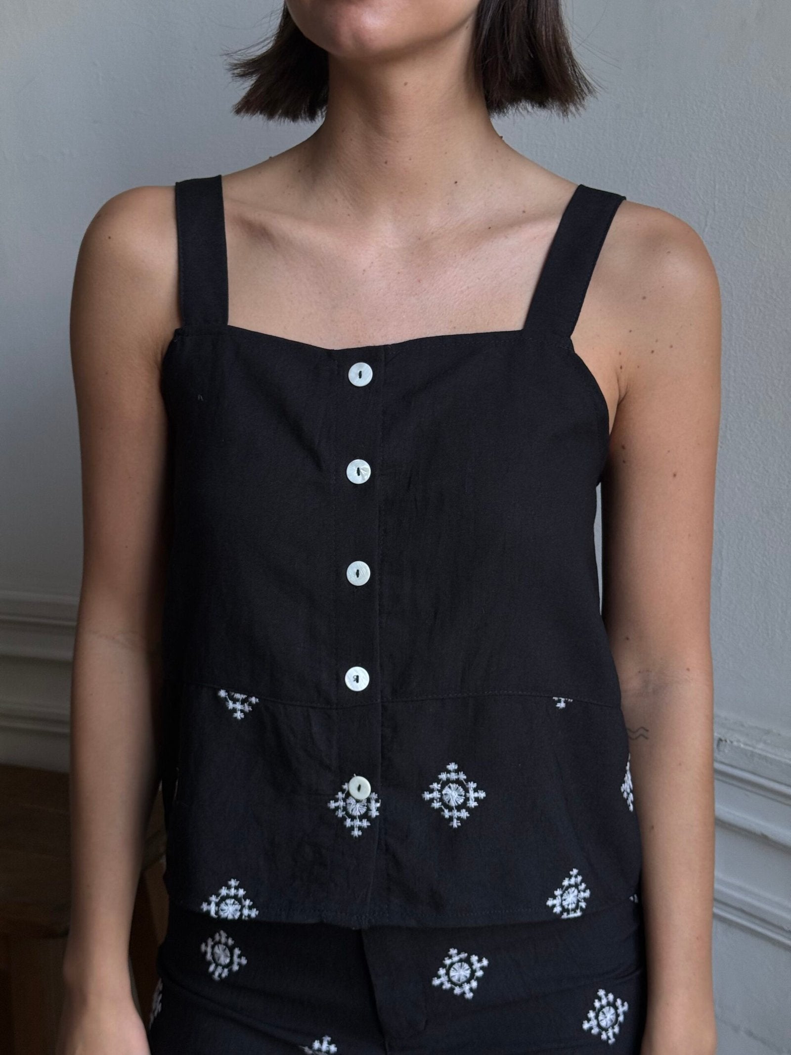 Remera negra sin mangas con escote cuadrado y botones blancos