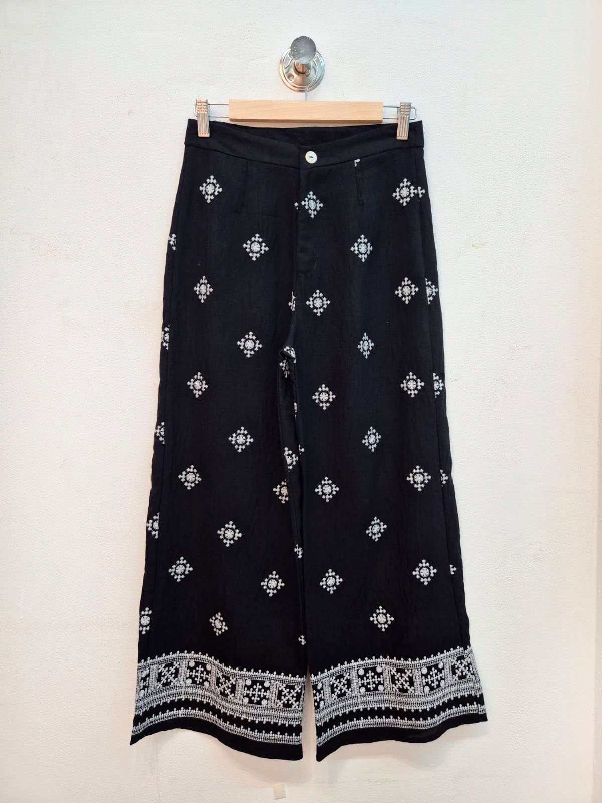 Pantalón negro con motivos geométricos blancos y borde bordado