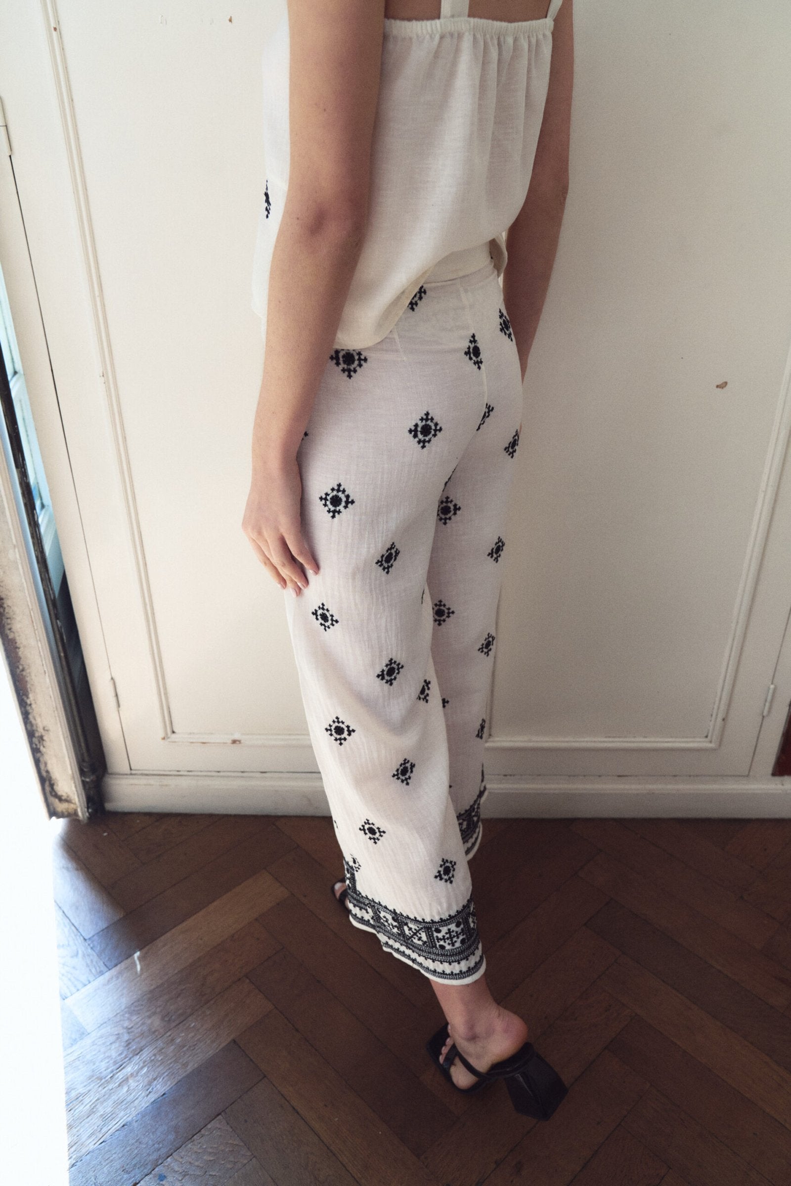 Pantalón blanco con estampado de motivos negros y borde acanalado