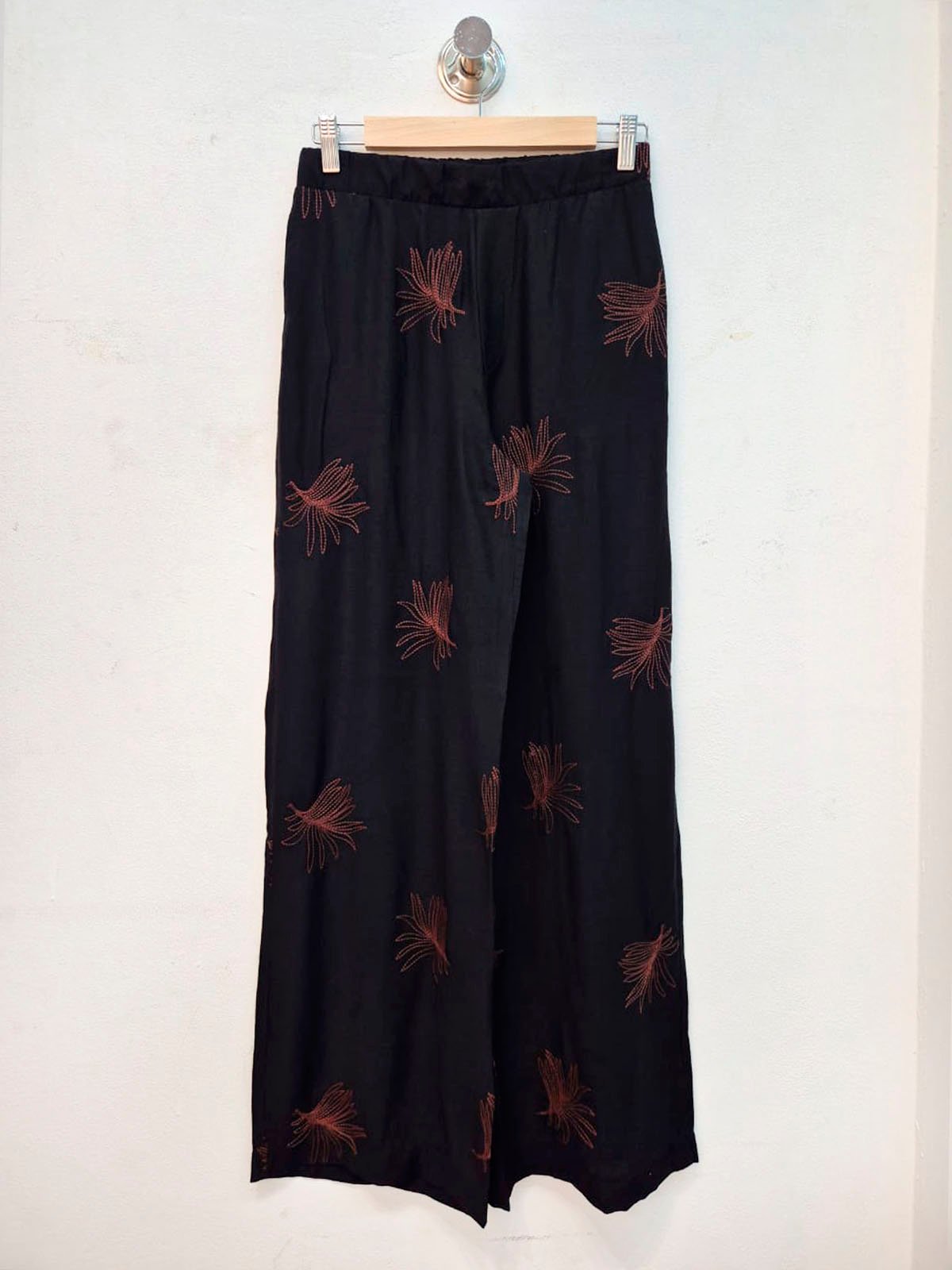 Pantalón negro con bordados rojos en motivo floral y pierna ancha