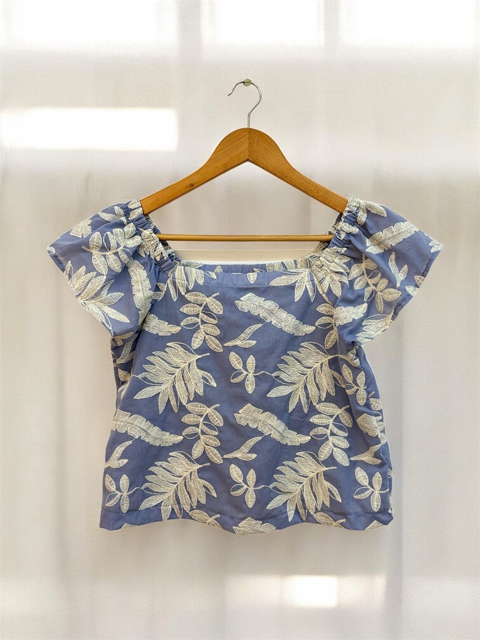 Blusa azul marino con estampado floral dorado y manga corta volada