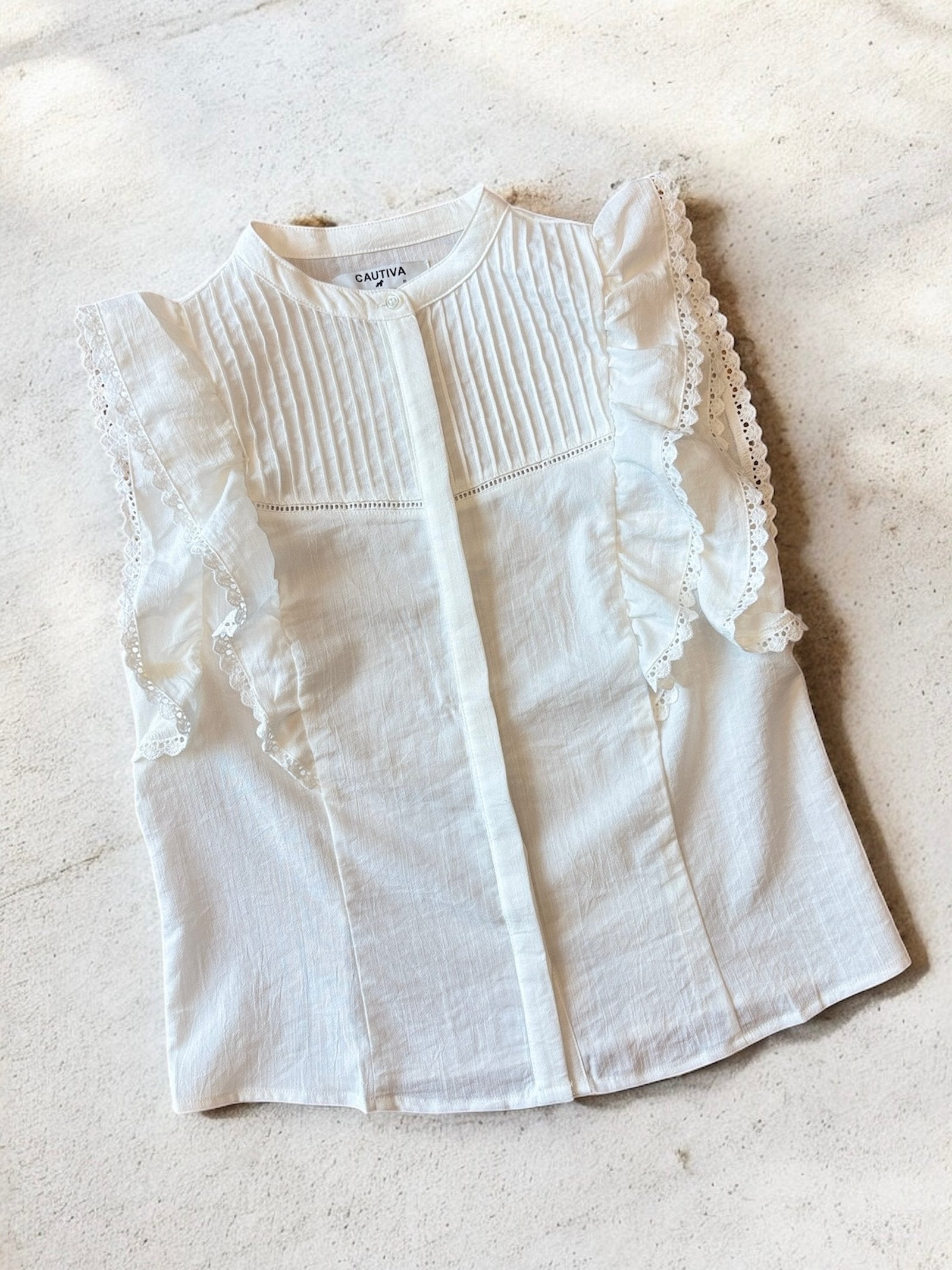 Camisa blanca sin mangas con pliegues y volantes de encaje