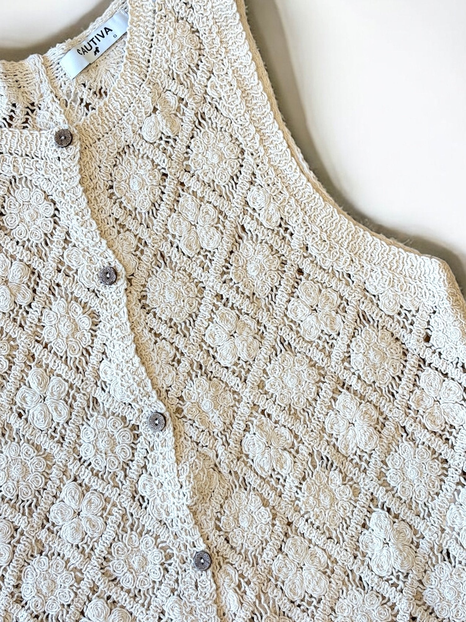 Chaleco de encaje blanco y beige con botones metálicos
