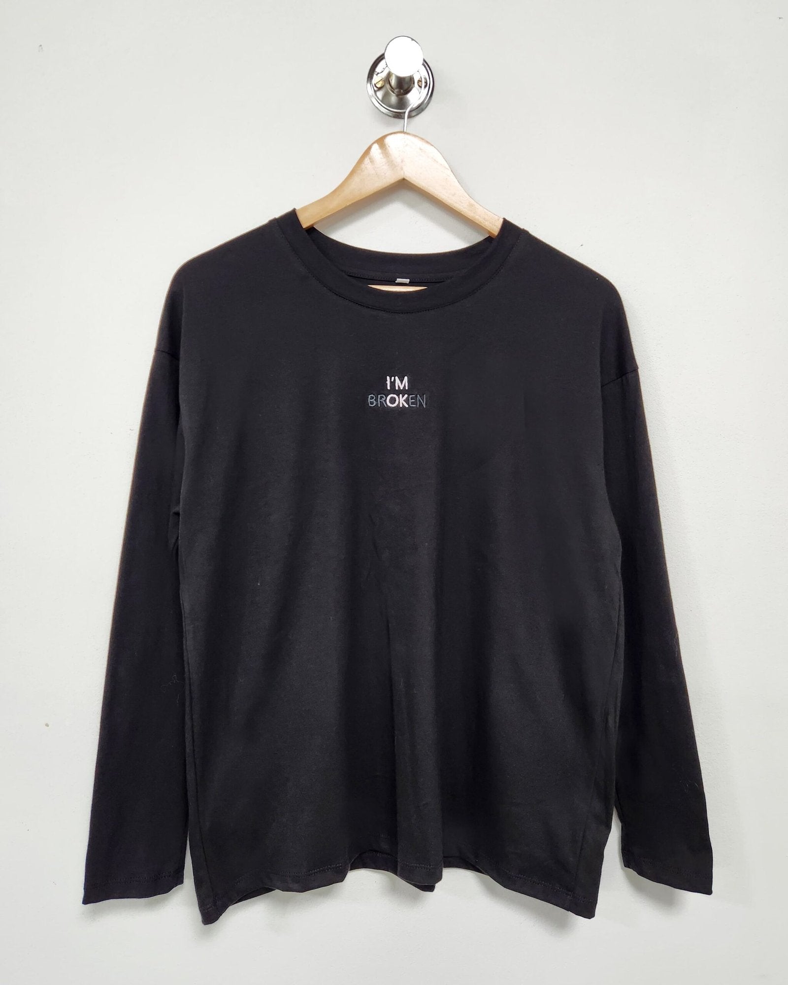 Remera negra de manga larga con estampado de texto pequeño en pecho