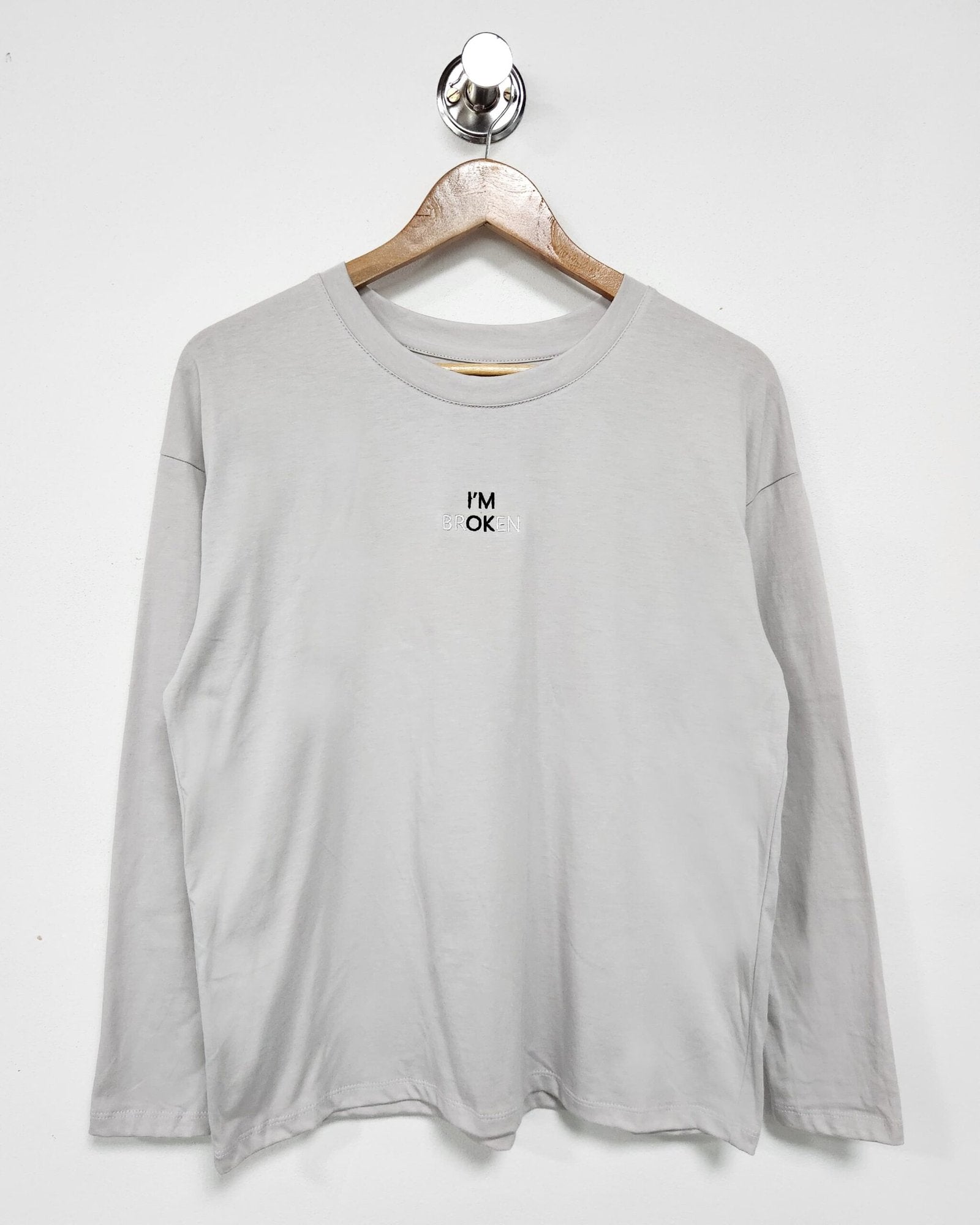 Remera gris claro de manga larga con estampado de texto pequeño